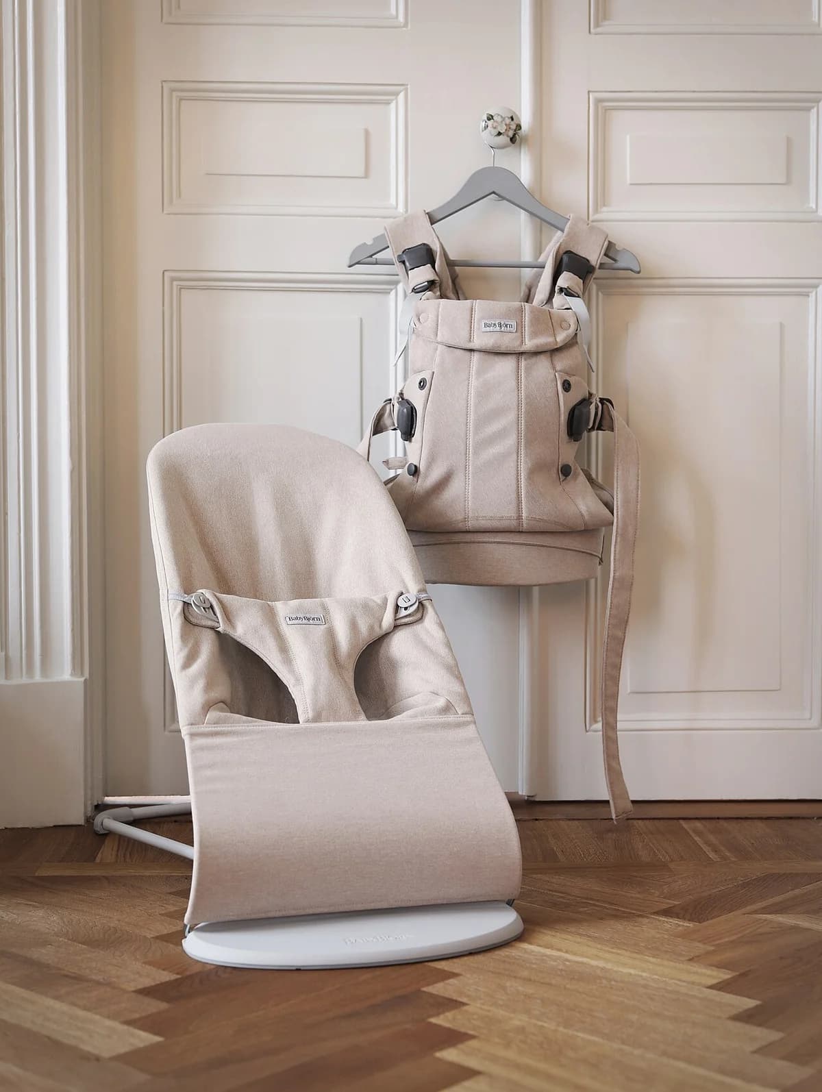 A beige BabyBjörn baby carrier and bouncer displayed indoors.