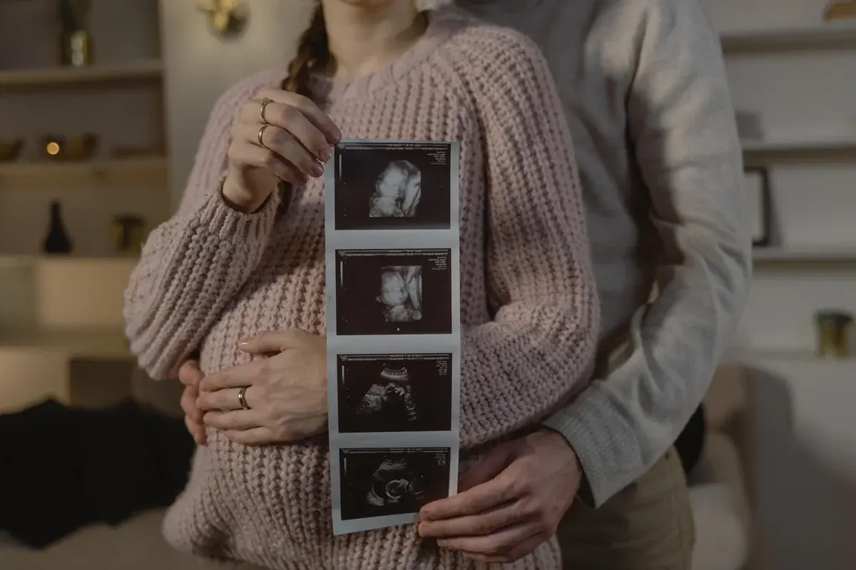 An expectant couple holding ultrasound images indoors.