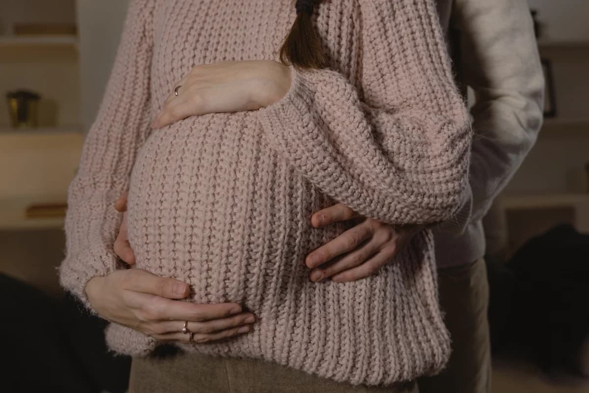 Close-up of a couple hugging a pregnant belly.