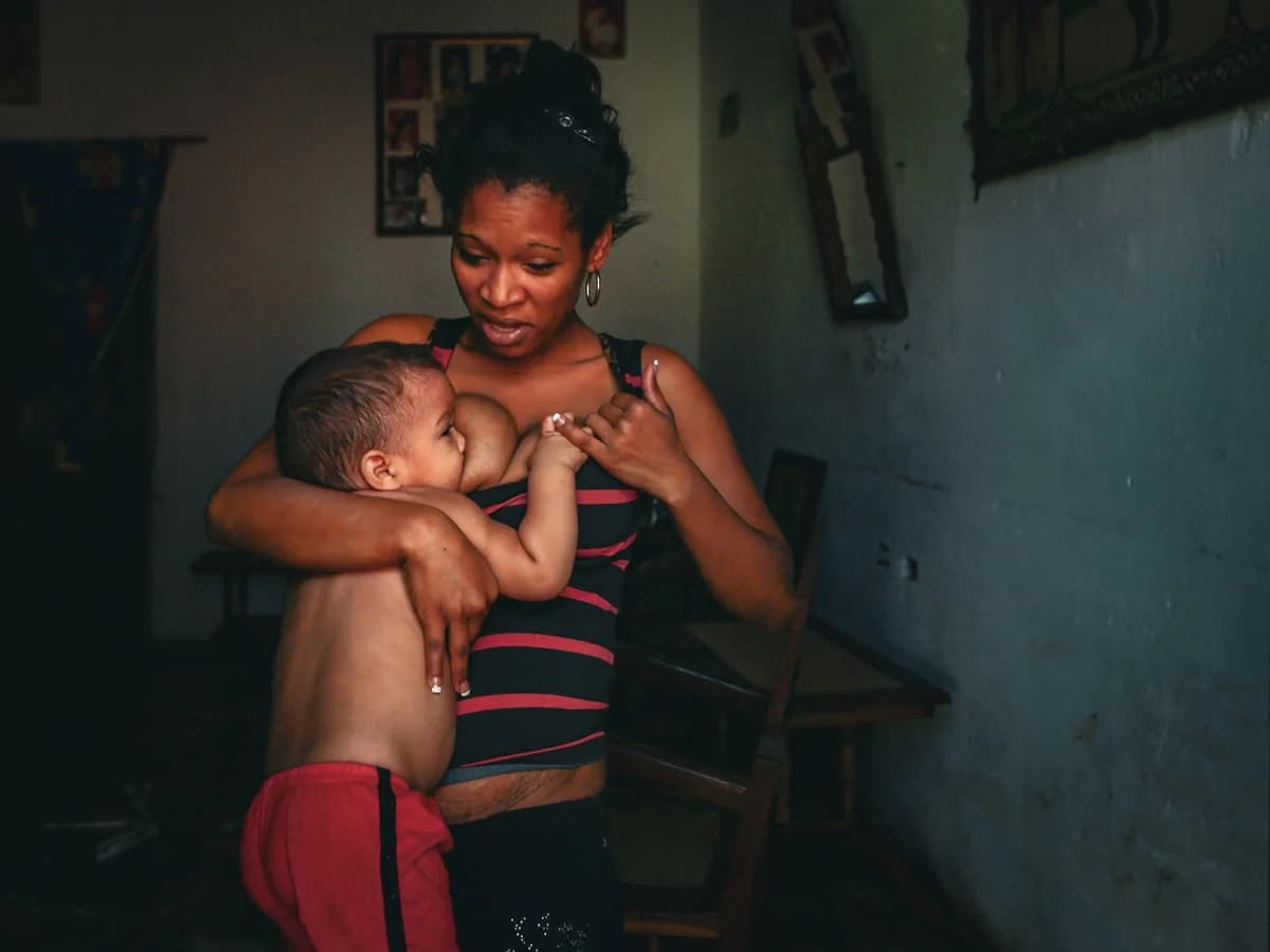 A mother breastfeeding her child indoors.