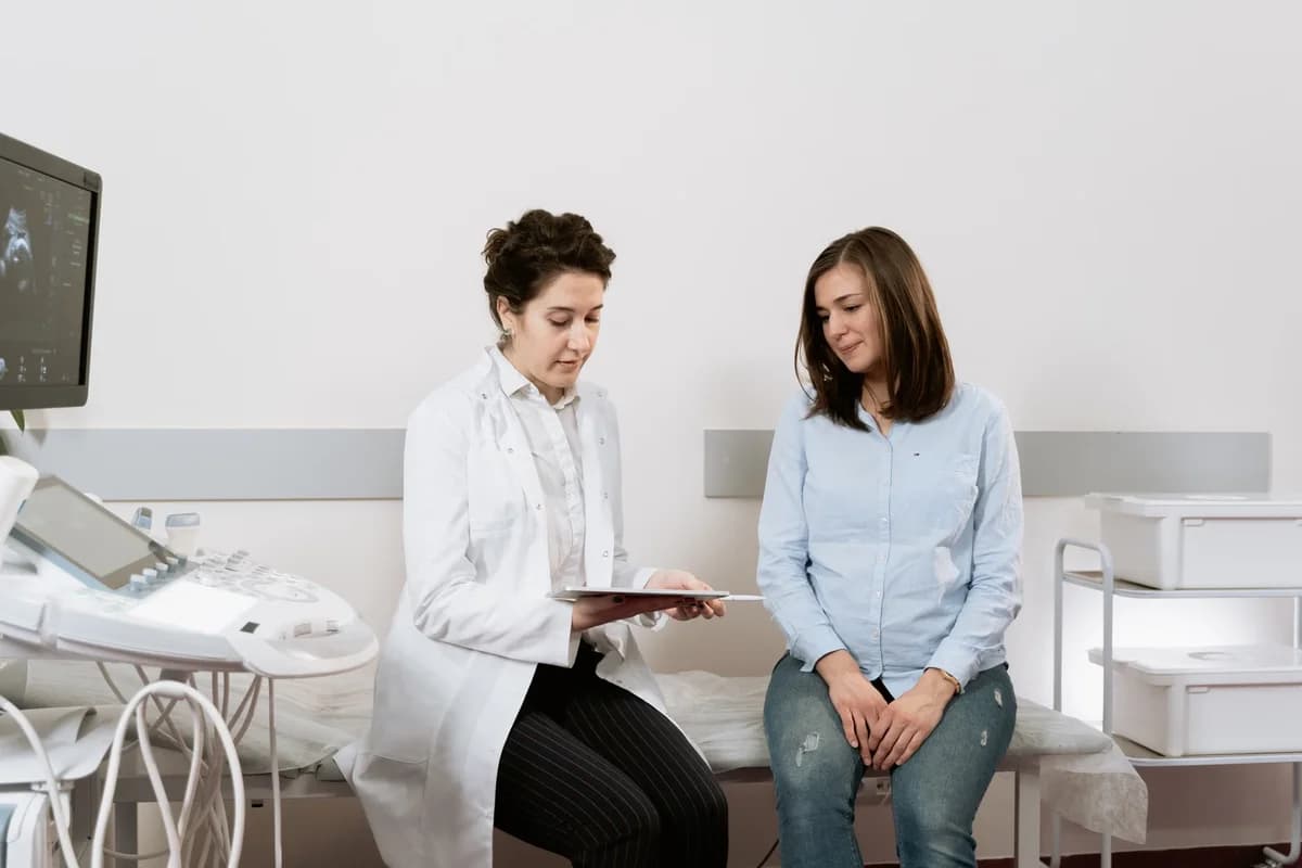 A pregnant woman speaking with a gynecologist in a clinic.