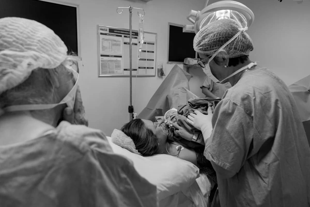 Doctors in a hospital delivery room with a mother and newborn baby.