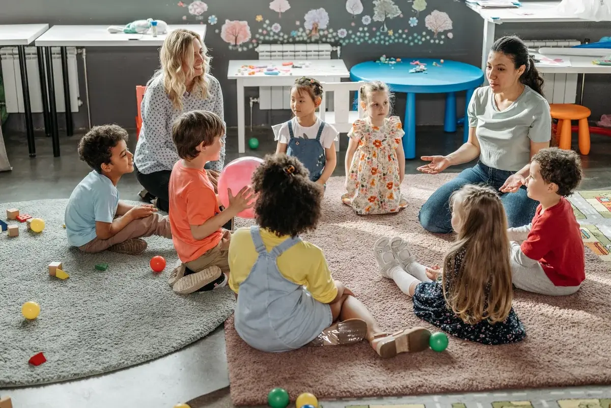 Children and two teachers sitting in a circle during a classroom activity.