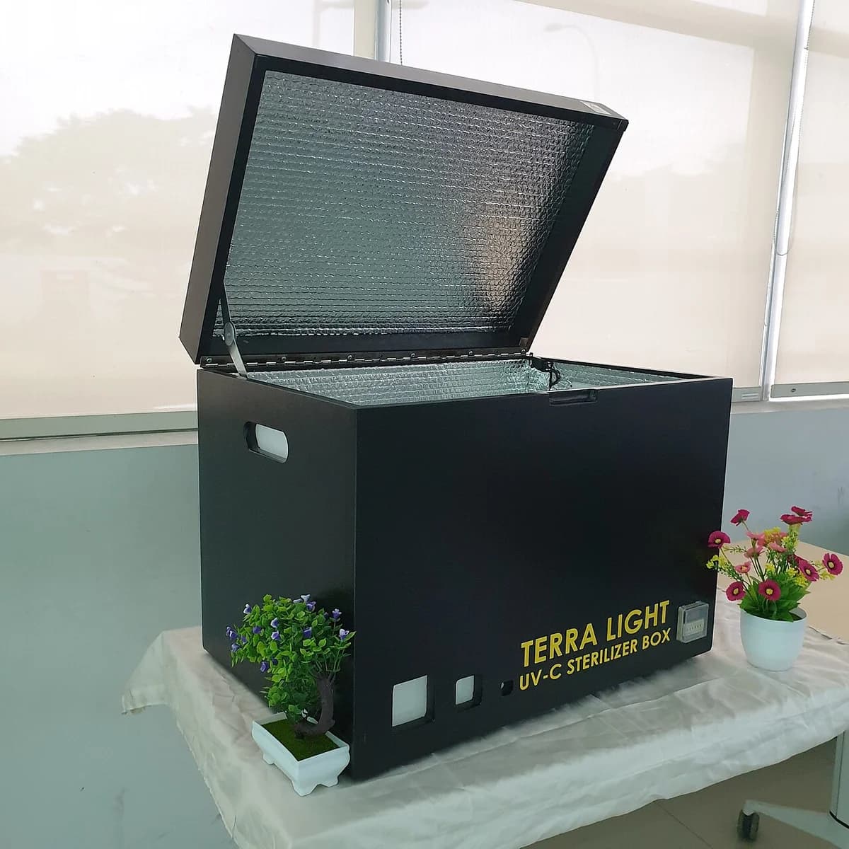 An open black UV-C sterilizer box on a table indoors.