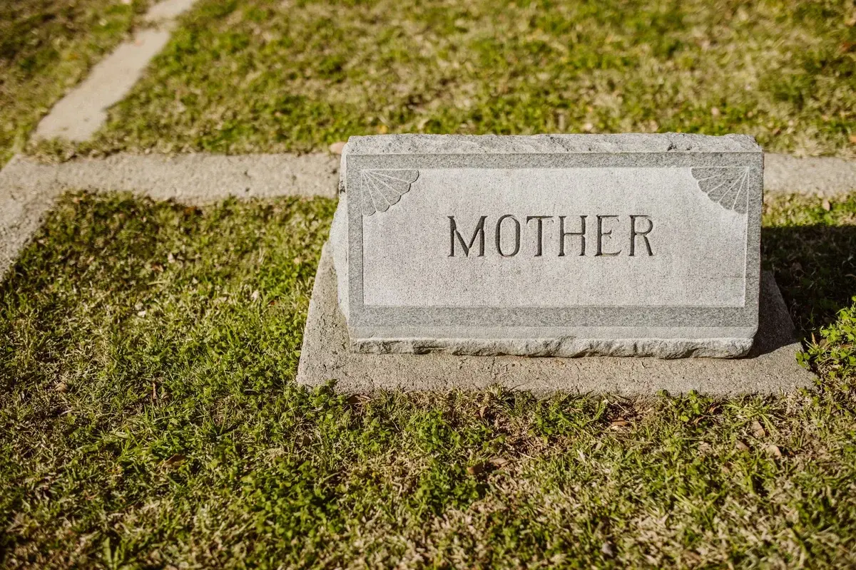 A gravestone engraved with the word “Mother” on grass.