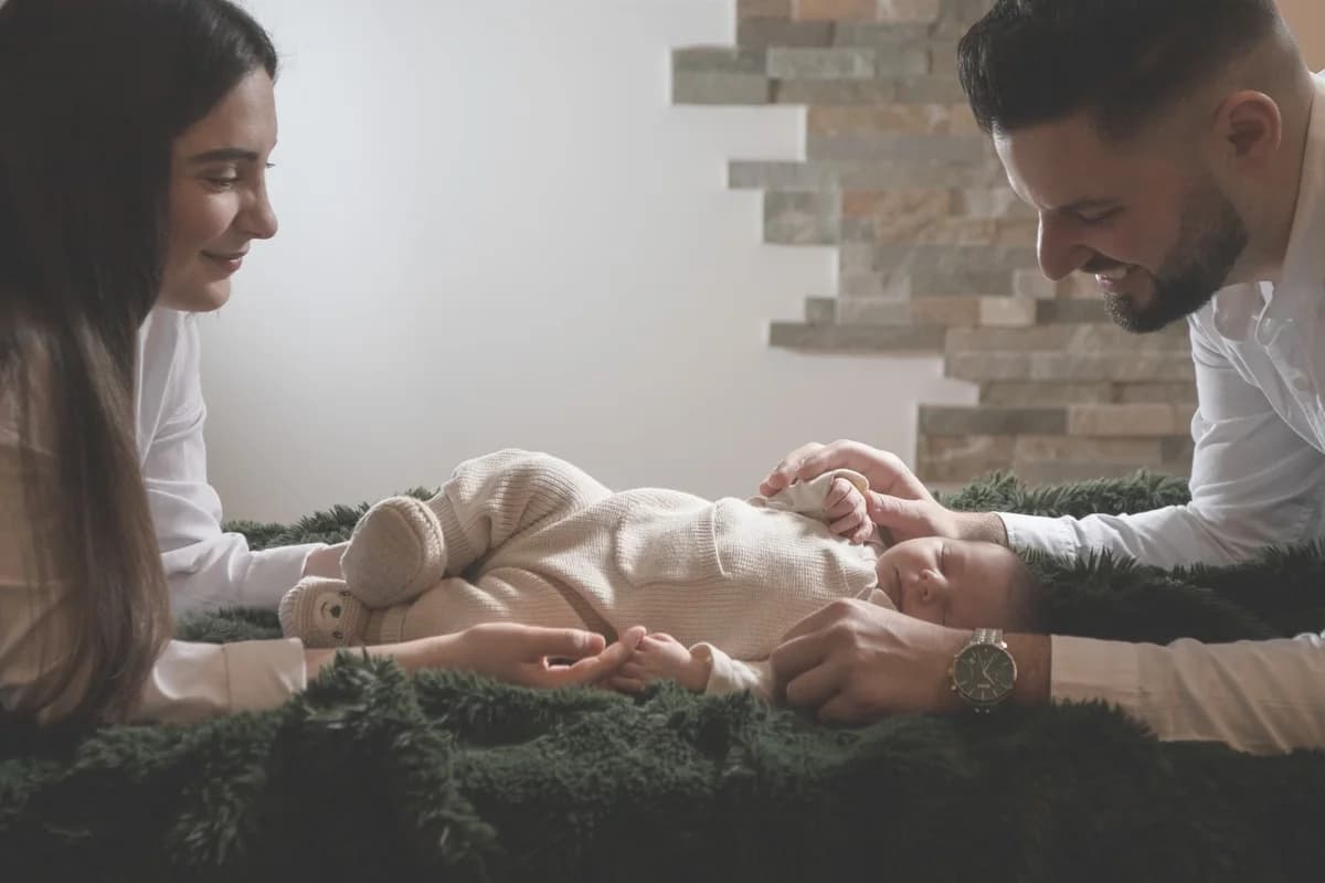 Parents gently holding their newborn baby indoors.